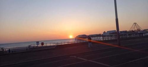 einen Sonnenuntergang über einem Strand mit Meer und einem Pier in der Unterkunft Meland (Families ONLY B&B) in Blackpool