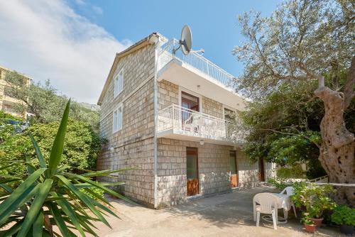 a brick house with a balcony on top of it at Apartmani Kuća u maslinama in Sveti Stefan