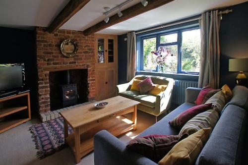 a living room with a couch and a fireplace at Cozy cottage overlooking fields, Upwell in Upwell