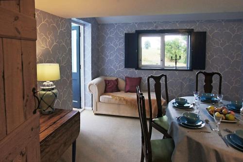 a dining room with a table and a couch at Cozy cottage overlooking fields, Upwell in Upwell