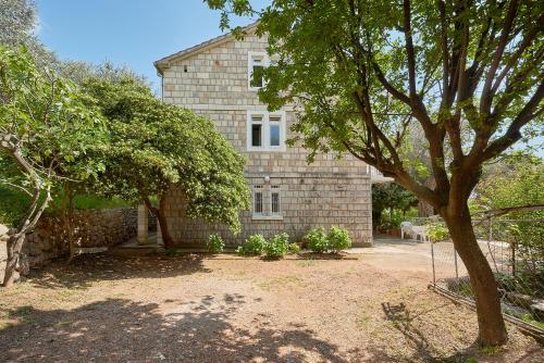 a large brick house with trees in front of it at Apartmani Kuća u maslinama in Sveti Stefan
