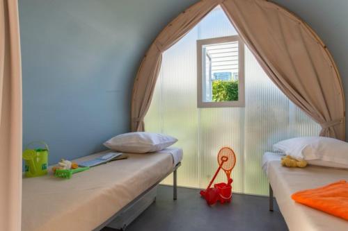 two beds in a room with a window at Camping Club l'Air Marin in Vias