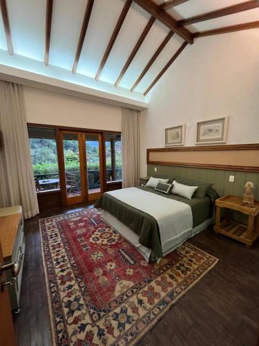 una camera con un grande letto e un tappeto di Chalé Quinta do Lago a Petrópolis