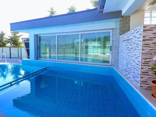 a swimming pool with a blue tile floor and a large window at Luander Hotel in Tirana
