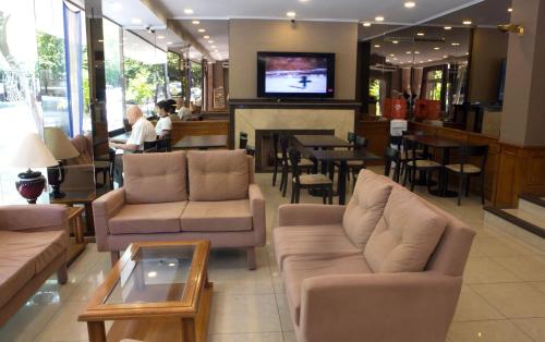 uma sala de estar com sofás e uma televisão e um bar em Ritz Hotel Mendoza em Mendoza