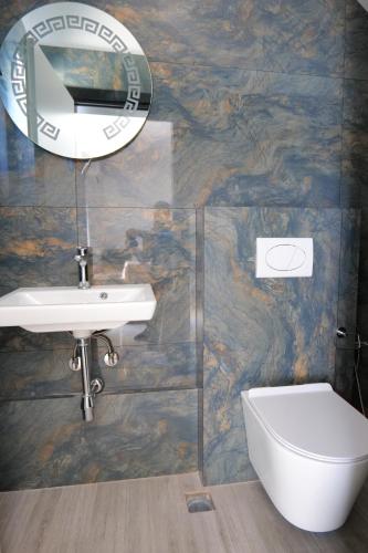 a bathroom with a sink and a mirror and a toilet at Vila Xhafa in Ksamil