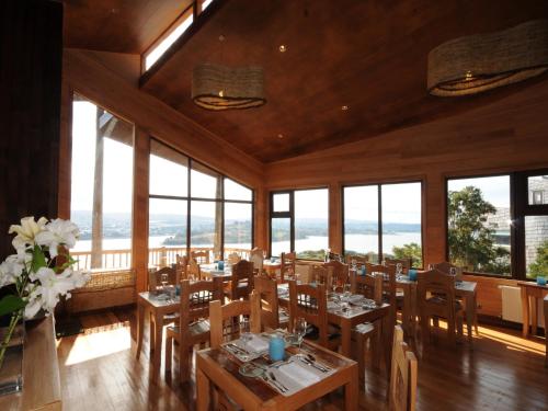a dining room with tables and chairs and windows at OCIO Territorial Hotel in Castro