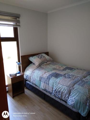 a bedroom with a bed and a table and a window at Casa en Pingueral in Tomé