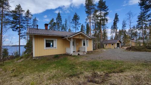 a small yellow house on top of a hill at Lake Cottage Jänisvaara in Kolinkylä