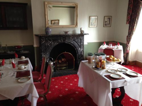 a dining room with two tables and a fireplace at Kirkgate House Hotel in Thirsk
