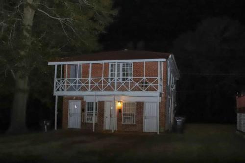 a small red brick house with a white porch at night at Historic House on the HillDownstairs ONLY in Tuskegee