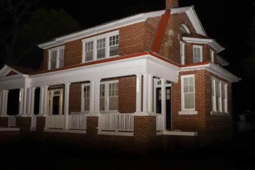 a red brick house with a white porch at night at Historic House on the HillDownstairs ONLY in Tuskegee
