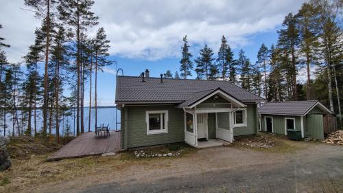 a small green house in the middle of a forest at Lake Cottage Jänisvaara in Kolinkylä