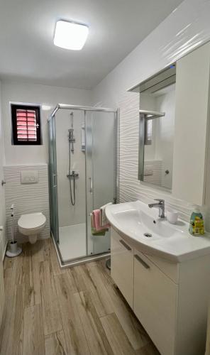 a bathroom with a sink and a shower and a toilet at Apartments Matušan in Rab