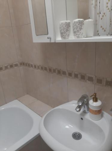 La salle de bains blanche est pourvue d'un lavabo et d'un miroir. dans l'établissement Apartman Poco, à Bijeljina