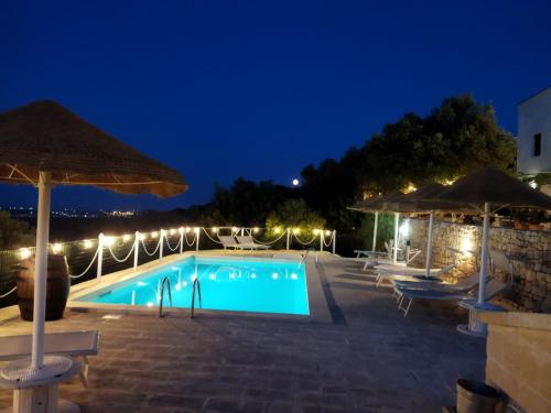 una piscina por la noche con sombrillas en B&B Pozzo Di Luce - Adults only, en Monopoli