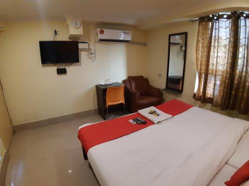 a bedroom with a bed and a chair and a television at Hotel Akash inn in Chennai