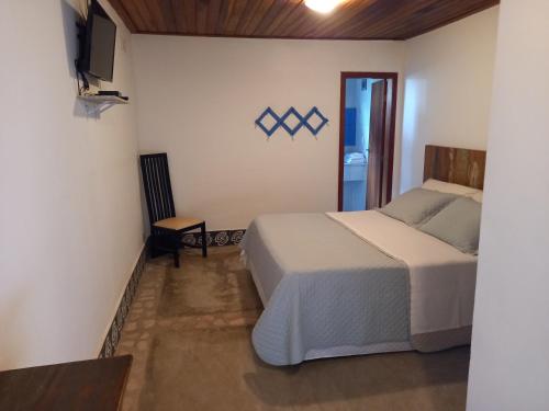 a bedroom with a bed and a tv on a wall at Pousada Serra Morena in Serra do Cipo