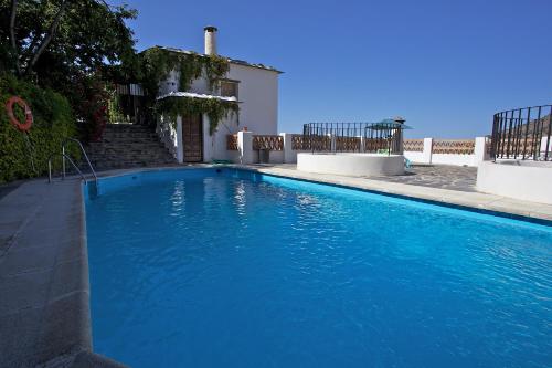 a blue swimming pool in front of a house at Casa Carole - 3 Bedroom Luxury Apartment in Bubión