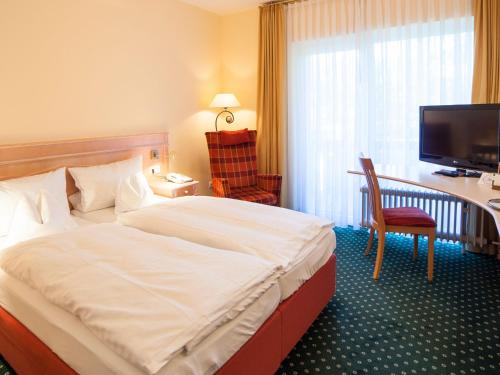 a hotel room with a bed and a desk and a television at Landhotel Der Schwallenhof in Bad Driburg