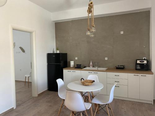 a kitchen with a white table and white chairs at Maganiotis House in Kimolos