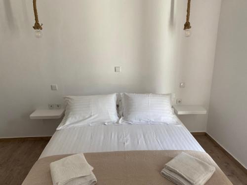 - une chambre avec un lit doté de draps et d'oreillers blancs dans l'établissement Maganiotis House, à Kimolos