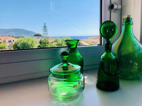 three green glass vases sitting on a window sill at InVilla Bed&Breakfast - Quality Rooms in Santa Maria di Castellabate