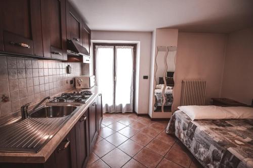 a kitchen with a sink and a stove and a bed at Residence Aquila - Mono Punta Valnera in Brusson