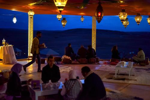 a group of people sitting in a tent at night at Agafay Pearl Camp Marrakech in Marrakech