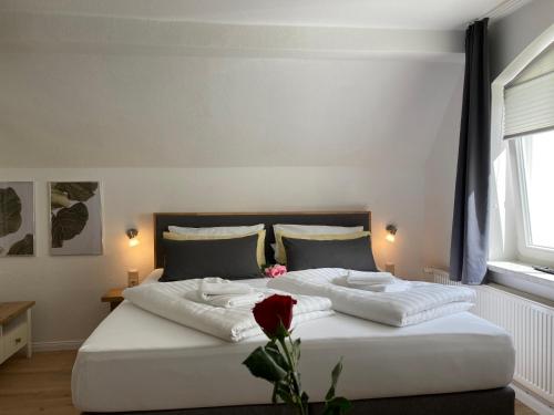 ein Schlafzimmer mit einem großen weißen Bett mit einer Rose darauf in der Unterkunft Appartement 6 ARA in Bergen auf Rügen