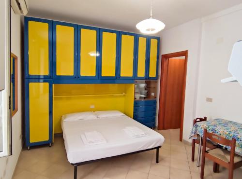 a room with a bed and yellow and blue cabinets at La cortese - By Ligooria in Pietra Ligure