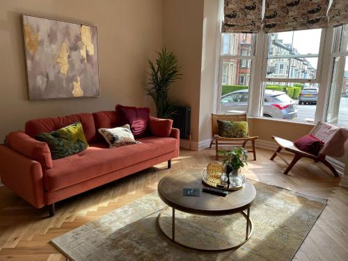 Una sala de estar con un sofá rojo y una mesa. en Maison Mouettes by Luxury Travel Emporium - Luxury Suites with Abbey Views, en Whitby