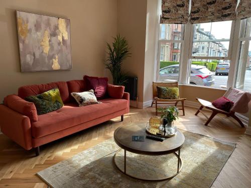 a living room with a red couch and a table at Maison Mouettes by Maison Parfaite - Luxury Suites with Abbey Views in Whitby