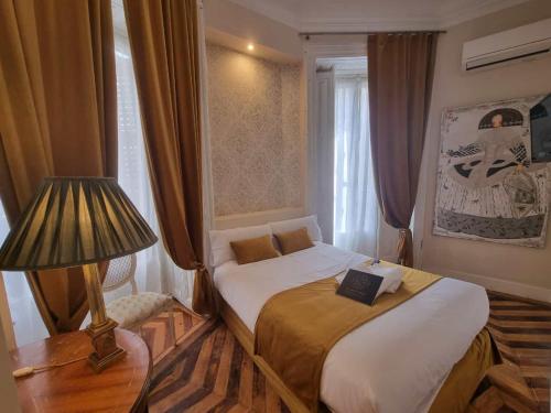 a bedroom with a bed and a lamp and a window at Le Petit Palü- Flora in Madrid