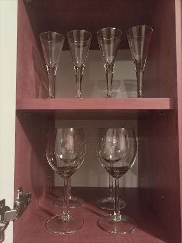 four wine glasses are sitting on a shelf at CAPPUCCINO CENTRUM Apartman in Kaposvár