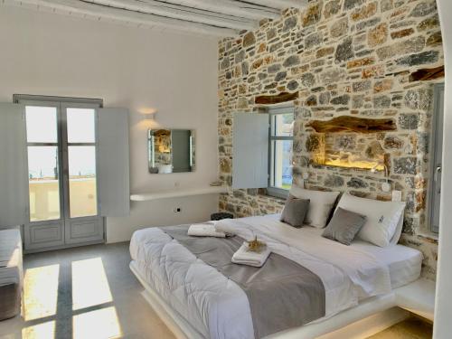 a bedroom with a large bed in a stone wall at Thomas Villas on the beach Katapola in Katapola