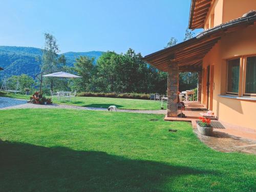 a backyard of a house with a green lawn at B&B Villa Claudia in Lavena Ponte Tresa