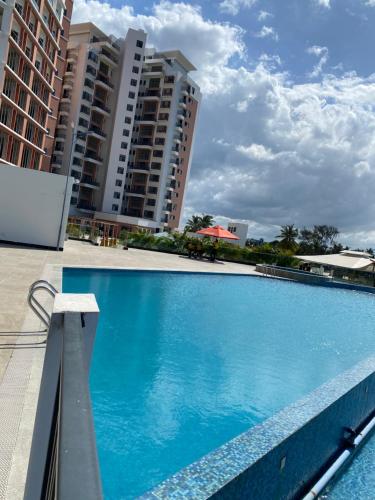 a large blue swimming pool with buildings in the background at Apartment X Palm Village Mikocheni in Dar es Salaam