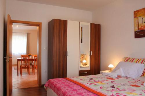 a bedroom with a bed and a dining room at Apartmani Mladenka in Malinska