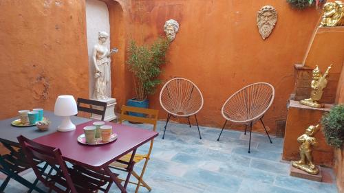 d'une terrasse avec une table, des chaises et une statue. dans l'établissement MAISON DE CHARME AVEC COUR, proche rue des Teinturiers, à Avignon