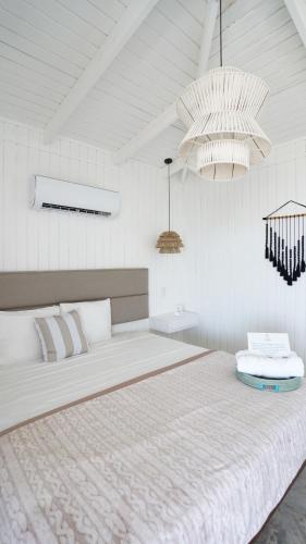 een witte slaapkamer met een groot bed met 2 kroonluchters bij Picuas Village in Rio Grande