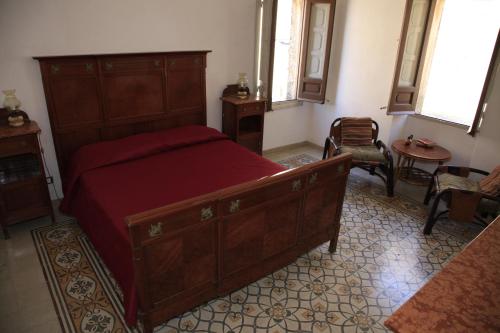 a bedroom with a large wooden bed with red sheets at SAN FRANCESCO 67 - Erice Vetta in Erice