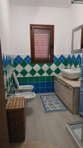 bagno con lavandino, servizi igienici e specchio di Appartamento Ziu Jori a Cala Liberotto