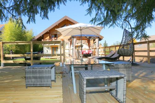 a house with a table and chairs and an umbrella at Chalet Savoyard Balcon de Villy in Étaux
