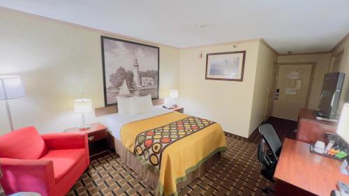 a hotel room with a bed and a red chair at Super 8 by Wyndham Maumee Perrysburg Toledo Area in Maumee