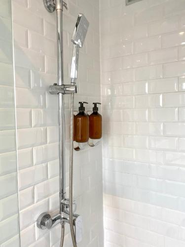 La salle de bains est pourvue d'une douche et de 2 bouteilles murales. dans l'établissement les suites du beffroi 2, à Calais