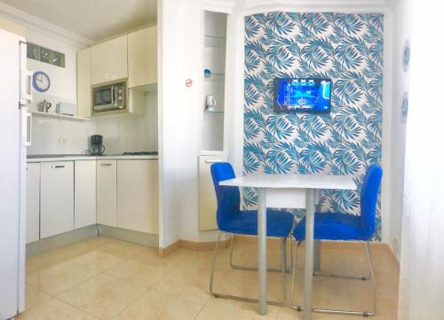 una pequeña cocina con mesa y sillas azules en Apartamentos Los Banquitos en Las Eras