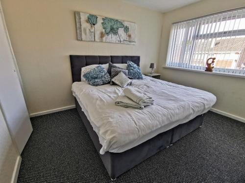 a bedroom with a large bed with blue pillows at Goldthorn Wolverhampton sleeps 5 long term comfortably and families in Wolverhampton
