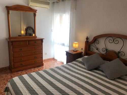 - une chambre avec un lit, une commode et un miroir dans l'établissement Piso en Pedregalejo a 50m de la playa., à Malaga
