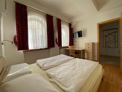 a bedroom with two beds and a desk in it at Saskia Apartments in Ortisei